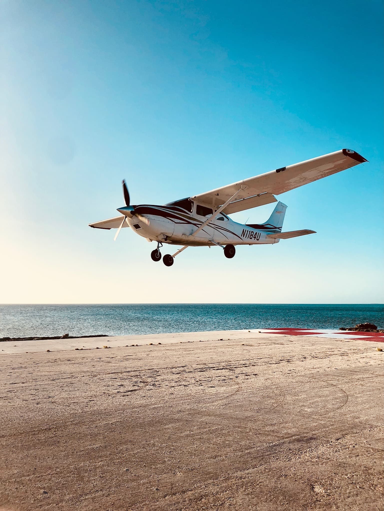 A Cessna moments from touchdown on a seaside runway