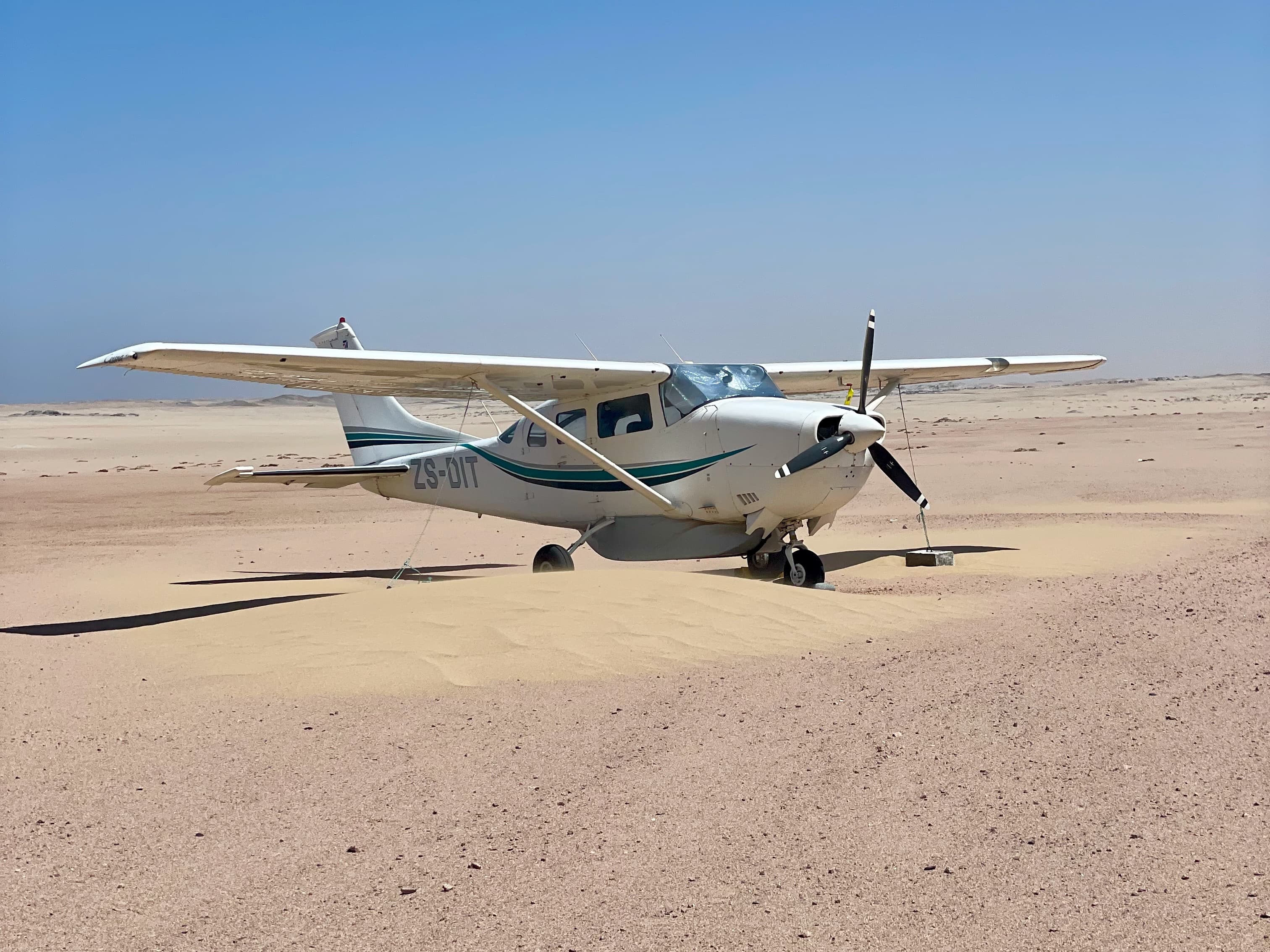 A Cessna 206 tied down on a remote desert strip